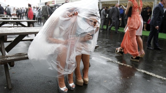 Two ladies shelter from the rain at the Grand National meeting at Aintree in April