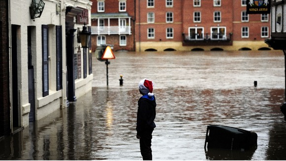 A young Christmas shopper looks at flood water in York city centre