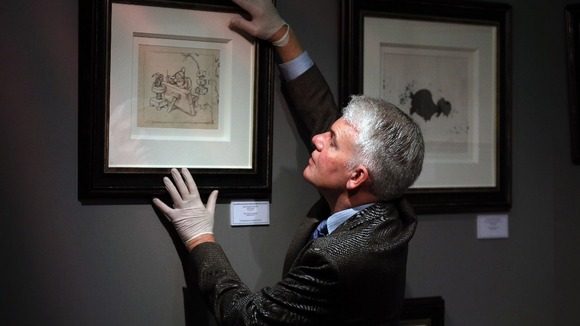 Fine Art and Antiques Consultant Duncan Phillips hangs the original artwork from Walt Disney's 'Snow White and the Seven Dwarfs' movie