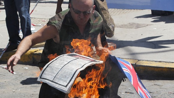 A protester sets fire to the paper with The Sun advert
