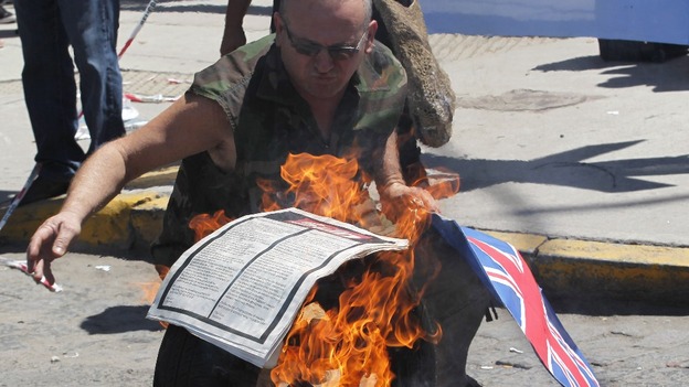A protester sets fire to the paper with The Sun advert