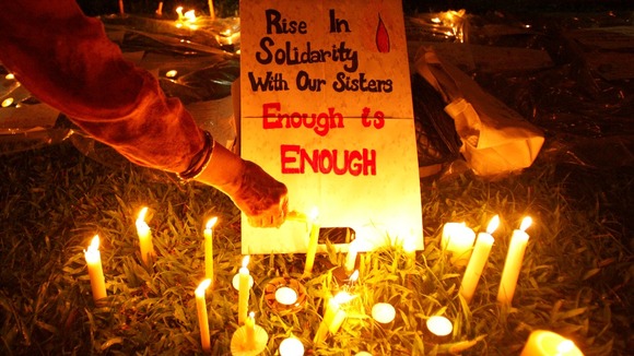 A participant lights a candle next to a sign during a vigil for the Indian rape victim