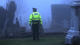 Police look on as the grave is refilled this afternoon.