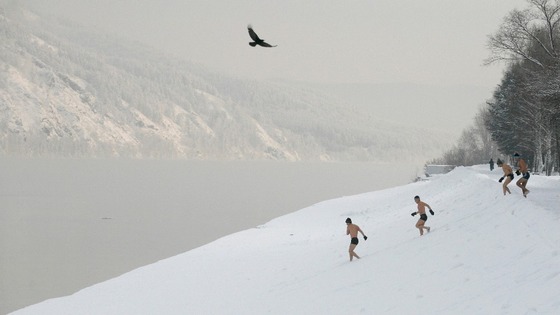 Members of the swimming club decend down the bank of the Yenisei River.
