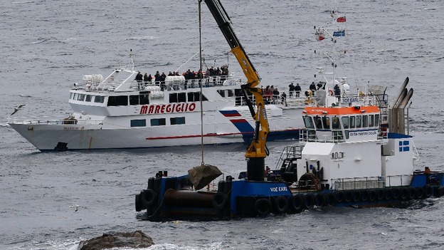 Workers drop a stone with a plaque into the sea during a ceremony to commemorate the first anniversary of the Costa Concordia tragedy.