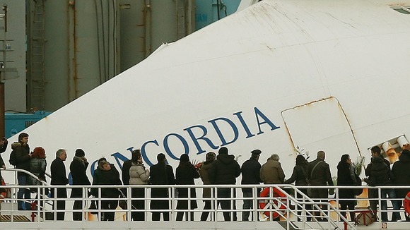 Relatives of victims stand on a ferry in front of the capsized cruise liner Costa Concordia outside Giglio harbour