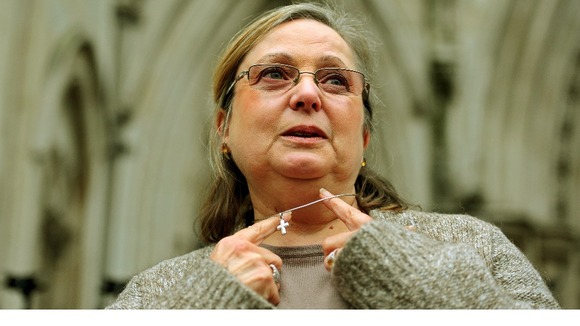 Britain's Nadia Eweida shows off her cross on a chain as she arrives at court in 2010
