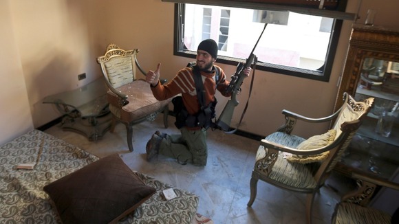 A Free Syrian Army fighter gestures after firing a rifle in the Ain Tarma neighbourhood of Damascus