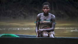 A young woman is pictured coated in oil stains as she sits in a canoe near river Nun in Nigeria's oil state of Bayelsa