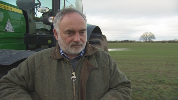 Farmer stands in front of tractor in field