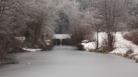 A river in Derbyshire appears frozen after overnight snow.