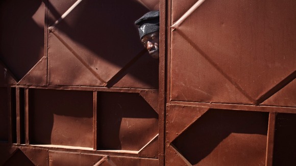 A Malian soldier peeks through a doorway behind where Malian and French soldiers are stationed in Niono.
