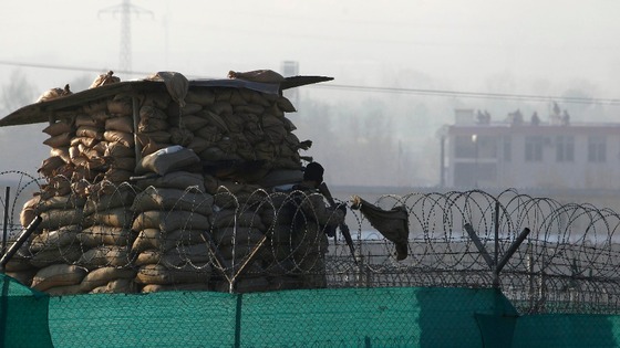 An Afghan police officer keeps watch as members of the Afghan security forces run on the roof