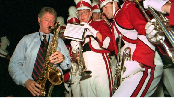 Bill Clinton plays the saxophone with members of the University of Arkansas marching band in 1992