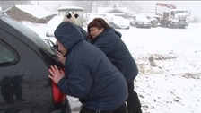 Carers pushing car out of snow