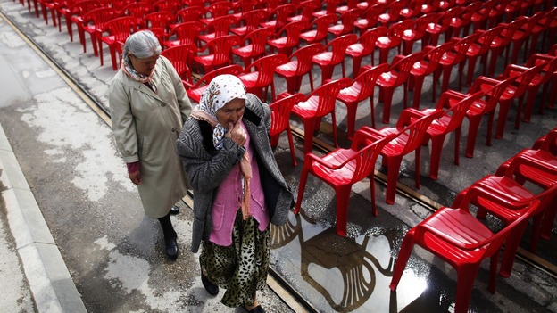 Women walk past some of the red chairs ahead of the official start of events for the 20th anniversary