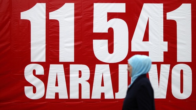 A woman walks near a banner with the number 11,541, to symbolise the red chairs