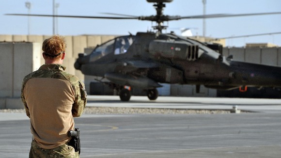 Harry watches the return from a mission of an Apache Helicopter