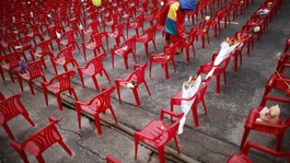 A child places a flower on a small chair symbolizing children killed