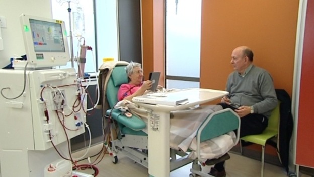 Woman in hospital bed talking to visitor