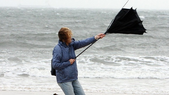 A woman struggles with her umbrella as high winds hit Tynemouth Beach, near Newcastle