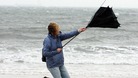 A woman struggles with her umbrella as high winds hit Tynemouth Beach, near Newcastle