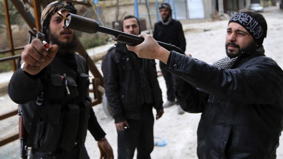 A Free Syrian Army fighter uses a shotgun to fire a homemade grenade