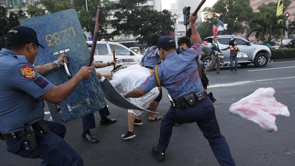 Anti-riot policemen use batons on a protester in Manila, Philippines