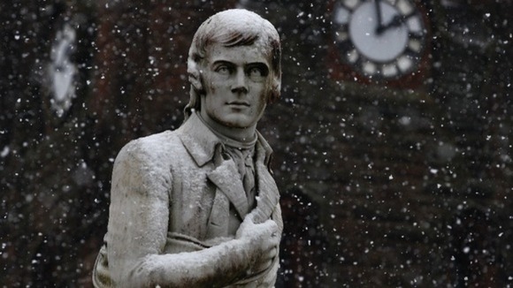 Snow falls onto a statue of Scotland's national poet, Robert Burns, in Dumfries