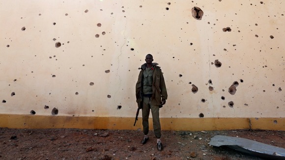 A Malian solider stands near a wall with bullet holes in the recently liberated town of Konna.