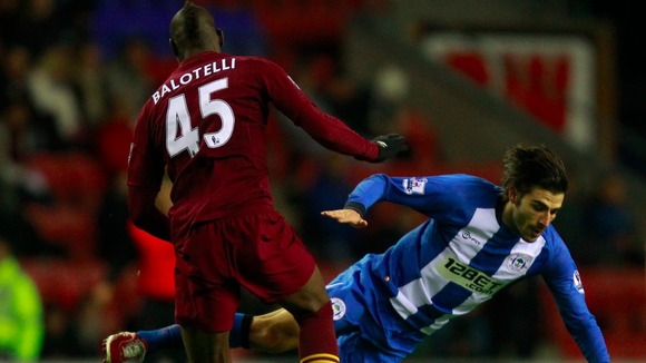 Balotelli tackles Wigan Athletic's Jordi Gomez