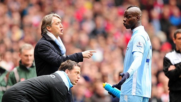 Balotelli (right) receives advice from manager Roberto Mancini