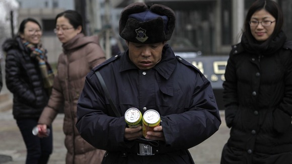 A bewildered security guard reads the cans