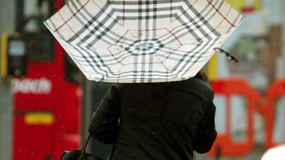 A worker in central London gets caught in strong wind and rain