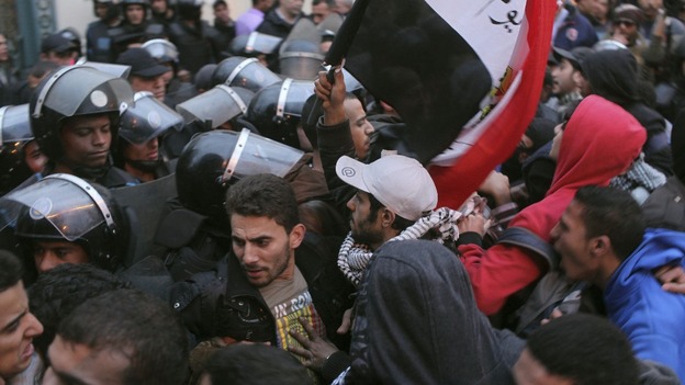 Police and protesters scuffle as protesters try to break through a gate of the presidential palace during protests in Cairo.