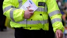 A policeman distributes witness appeal leaflet