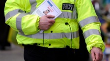 A policeman distributes witness appeal leaflet