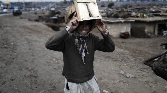 A boy uses a crate to take shelter from the rain