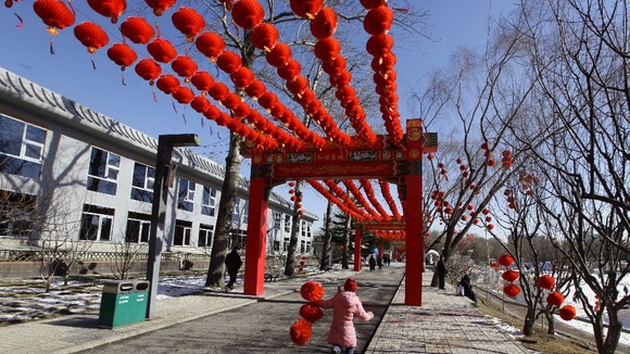 A girl holding red lanterns used for decoration runs in a park ahead of Chinese New Year celebrations.