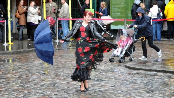reet entertainer Dolores Delight entertains crowds queuing in the rain in London's Covent Garden, on a wet Bank Holiday Monday.