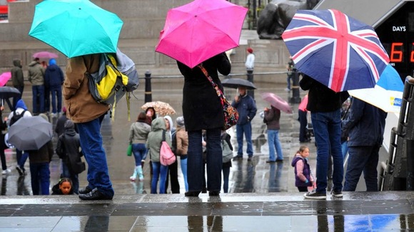 Visitors armed with umbrellas in Trafalgar Square, London.