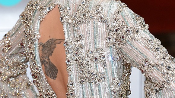 Paloma Faith shows off a tattoo to the press photographers