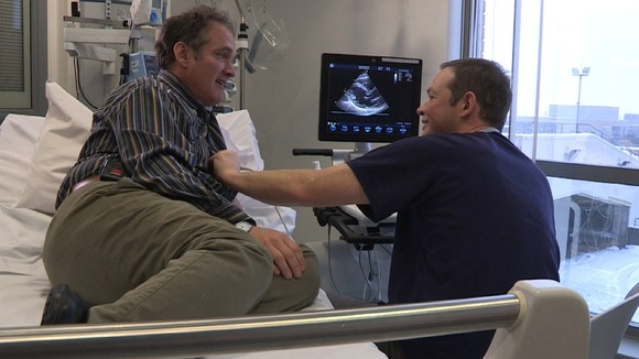 Middle aged man on hospital bed talking to doctor with stethoscope