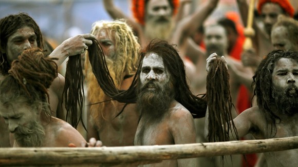 Naga Sadhus hold the hair of another Naga Sadhu on the banks of the Ganges at the ongoing "Kumbh Mela"