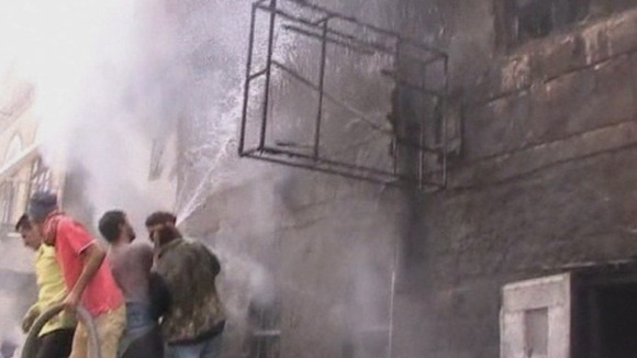 People climb onto the roof of a burned out car try an put a fire out.