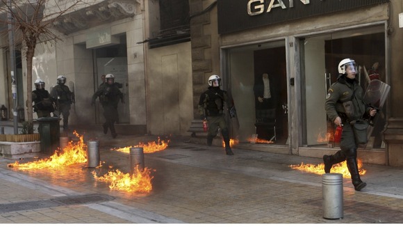 Riot police run by closed shops after protesters threw a petrol bomb