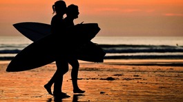 Two surfers leave the water and head back across the beach at Woolacombe, North Devon 