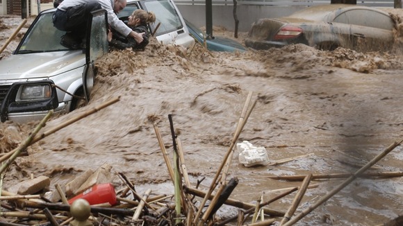 A local help man tries to help a woman caught in flooding in Athens