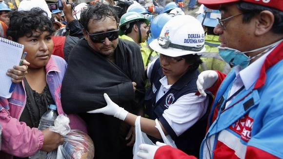 A rescued miner is escorted outside the mine this afternoon.