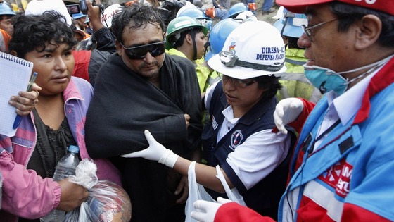 A rescued miner is escorted outside the mine this afternoon. 